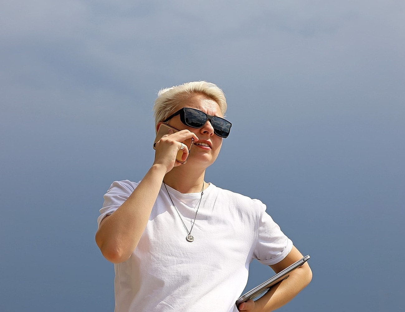 Person talking on phone outdoors, wearing sunglasses.