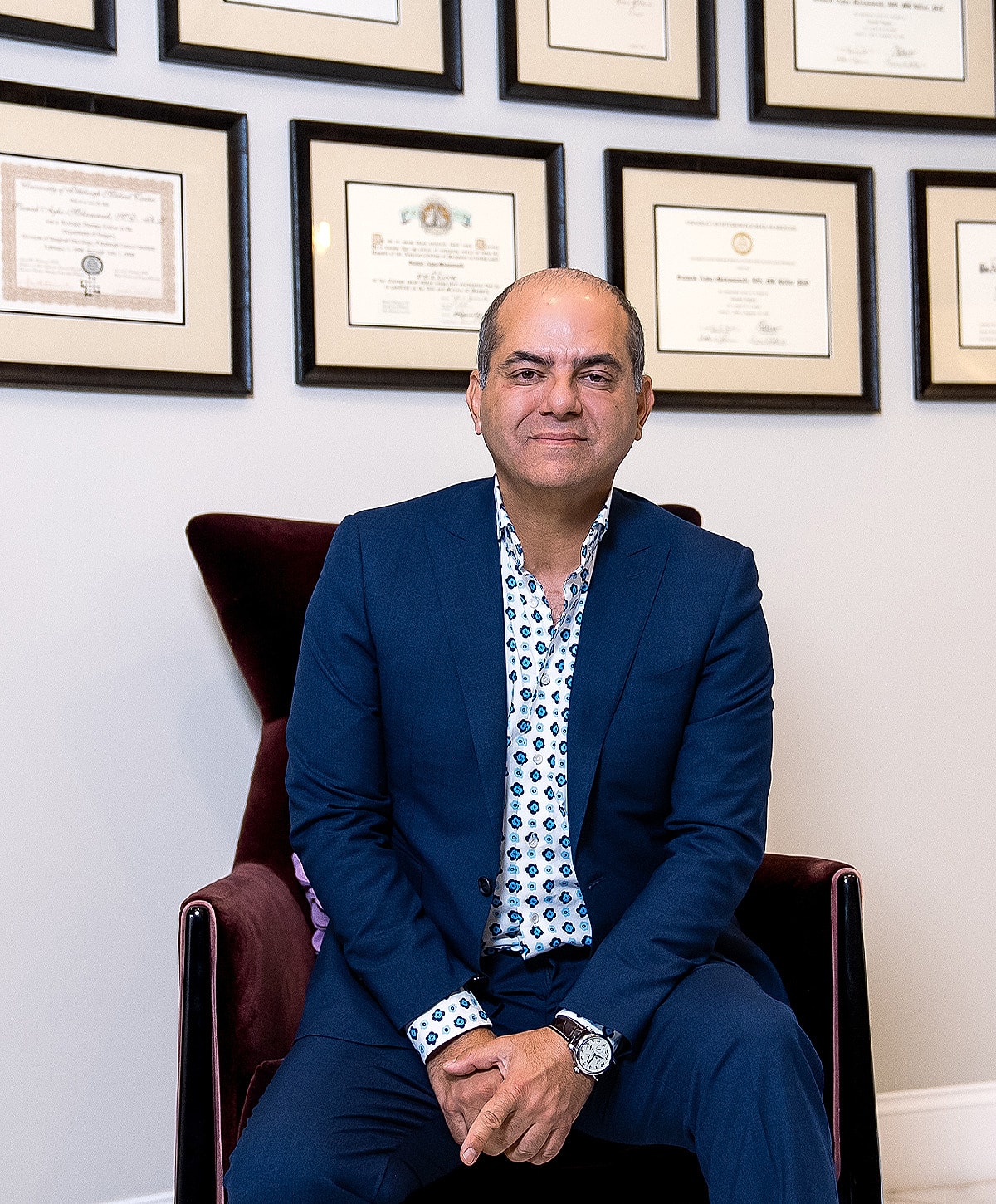 Professional man seated with framed certificates background.