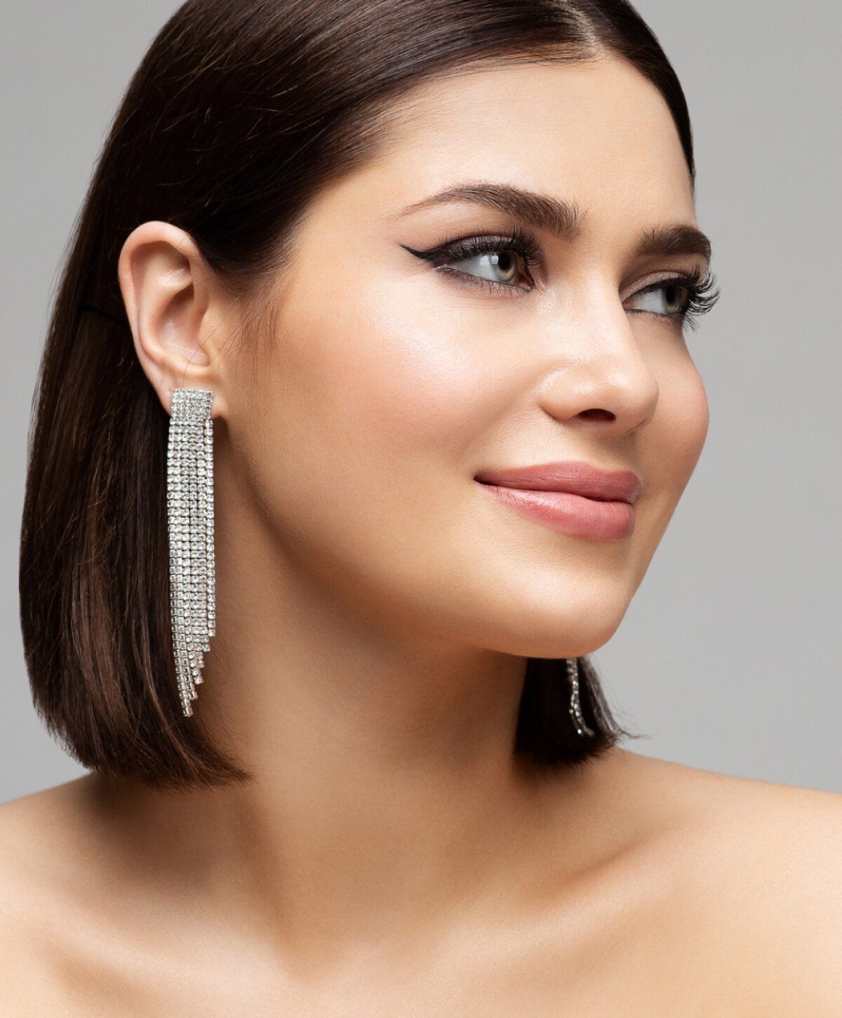 Model showcasing elegant dangling earrings and makeup.
