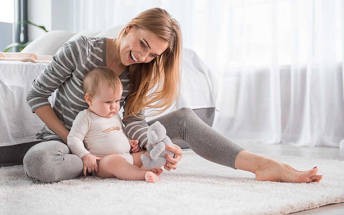 Mother and baby playing on a soft rug.