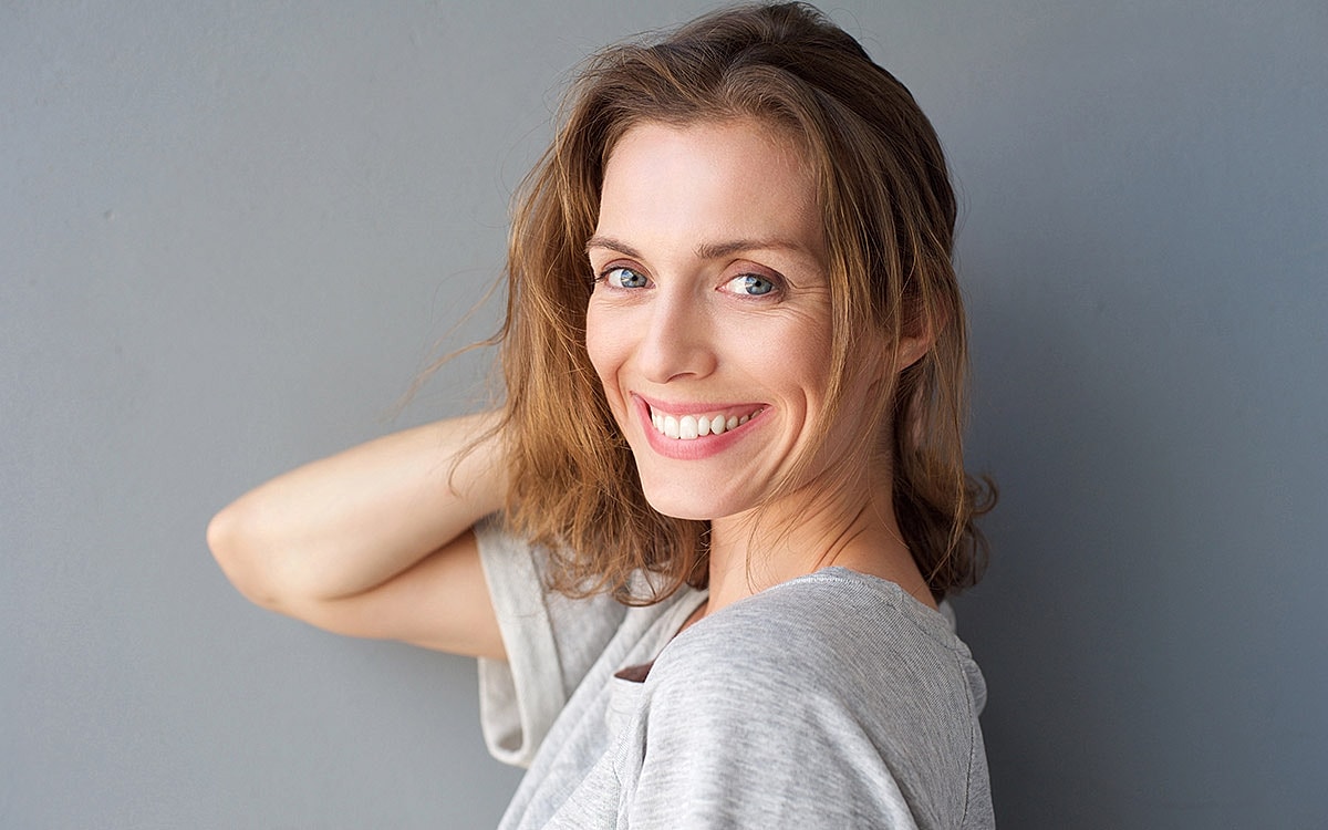Smiling woman with casual hair and grey background