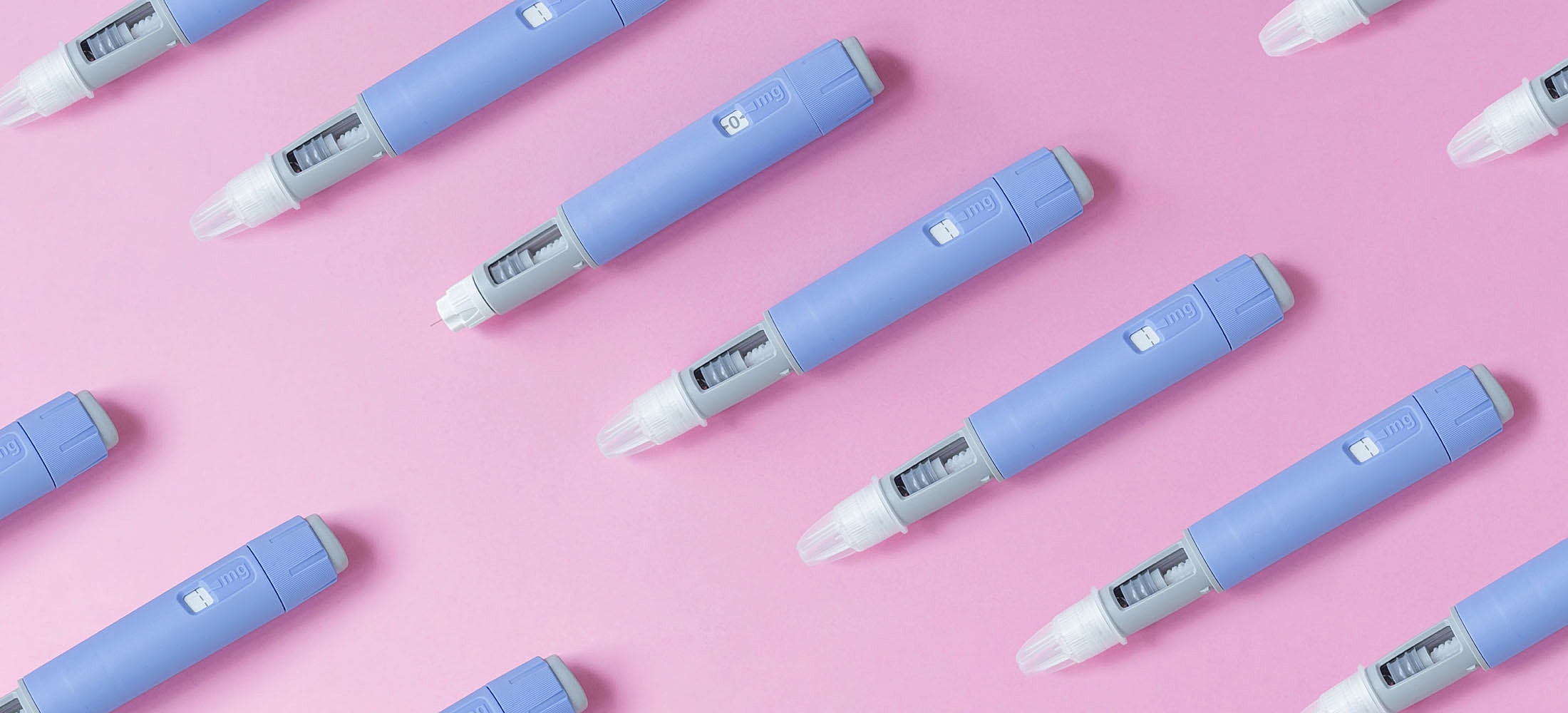 Blue injector pens on pink background.