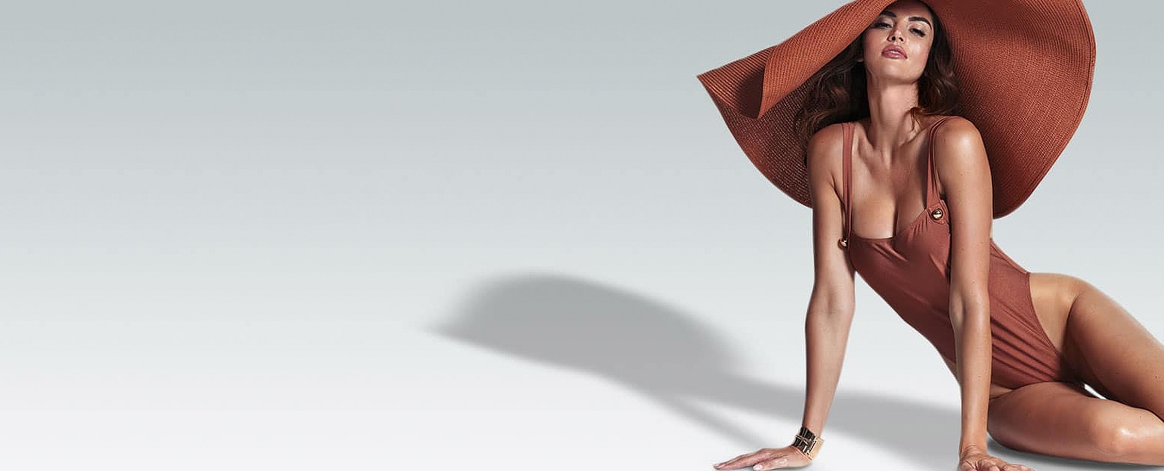Model in swimwear with oversized sun hat.