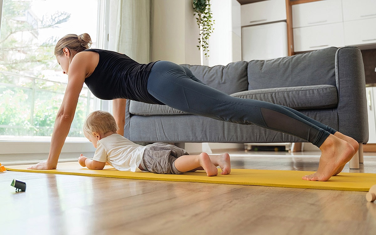 Woman exercising while toddler plays nearby.