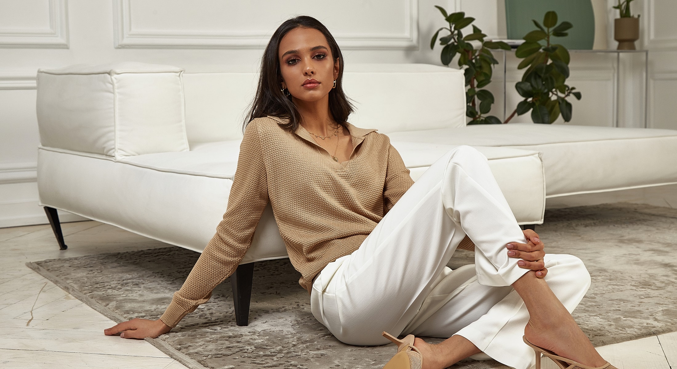 Woman in stylish outfit lounging on sofa.