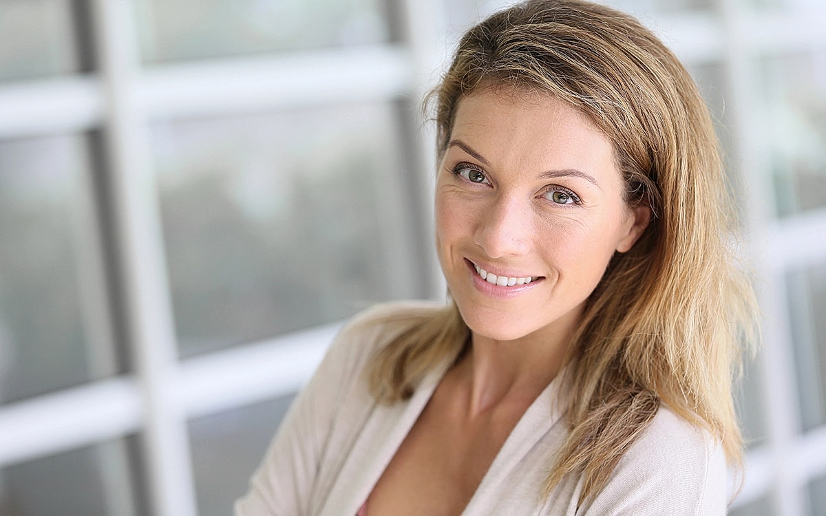 Smiling woman with light brown hair indoors.