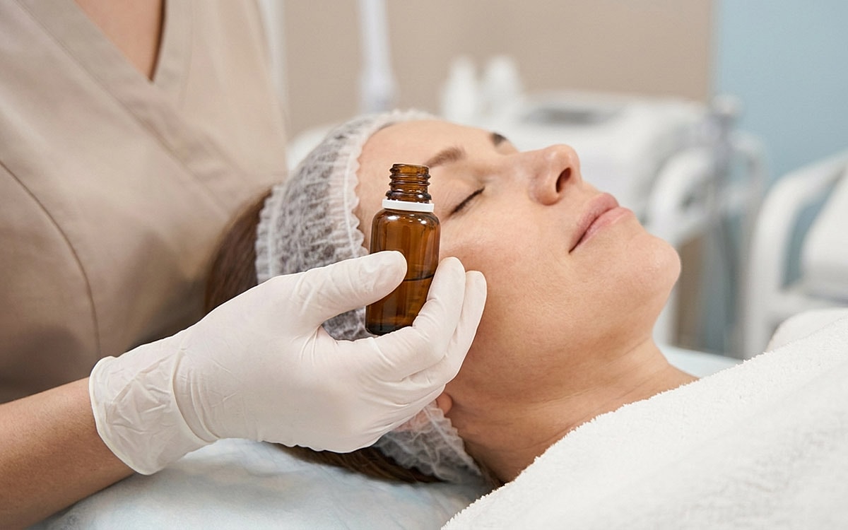woman holding a small skincare dropper near patients cheek