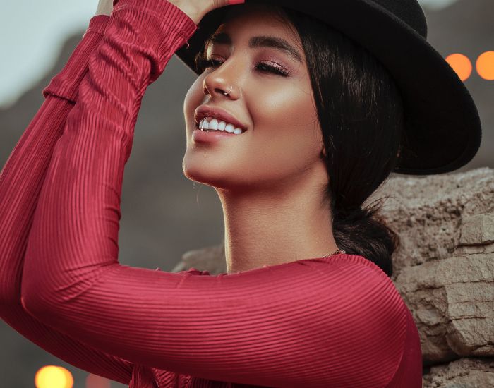 Smiling woman in red shirt and black hat.